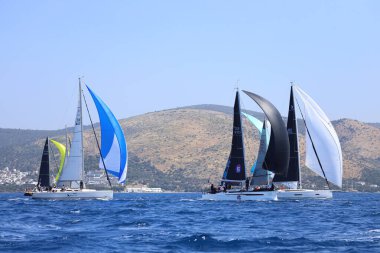 Bodrum, Hindi. 28 Nisan 2024: Yelkenliler Ege Denizi 'nin mavi sularında, ünlü tatil beldesi Bodrum' un kıyılarında rüzgarlı havada yelken açıyorlar..