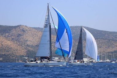 Bodrum, Hindi. 28 Nisan 2024: Yelkenliler Ege Denizi 'nin mavi sularında, ünlü tatil beldesi Bodrum' un kıyılarında rüzgarlı havada yelken açıyorlar..