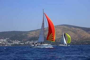 Bodrum, Hindi. 28 Nisan 2024: Yelkenliler Ege Denizi 'nin mavi sularında, ünlü tatil beldesi Bodrum' un kıyılarında rüzgarlı havada yelken açıyorlar..