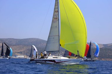 Bodrum, Hindi. 28 Nisan 2024: Yelkenliler Ege Denizi 'nin mavi sularında, ünlü tatil beldesi Bodrum' un kıyılarında rüzgarlı havada yelken açıyorlar..