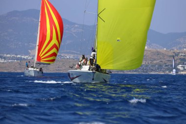 Bodrum, Hindi. 28 Nisan 2024: Yelkenliler Ege Denizi 'nin mavi sularında, ünlü tatil beldesi Bodrum' un kıyılarında rüzgarlı havada yelken açıyorlar..