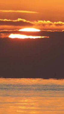 Güneş, denize batıyor. Görüntü akışını hızlandırmak mümkün. Sosyal medya için dikey video.