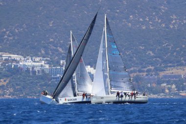 Bodrum, Hindi. 28 Nisan 2024: Yelkenliler Ege Denizi 'nin mavi sularında, ünlü tatil beldesi Bodrum' un kıyılarında rüzgarlı havada yelken açıyorlar..