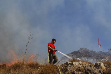 Bodrum, Hindi. 01 Ağustos 2020: Çimen tarlalarında, ormanlarda ve gökyüzüne siyah beyaz dumanlar saçan kırmızı ateş alevi. Yakından büyük bir yangın var. Hava konseptinde kirlilik.
