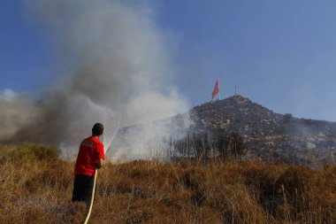 Bodrum, Hindi. 01 Ağustos 2020: Çimen tarlalarında, ormanlarda ve gökyüzüne siyah beyaz dumanlar saçan kırmızı ateş alevi. Yakından büyük bir yangın var. Hava konseptinde kirlilik.