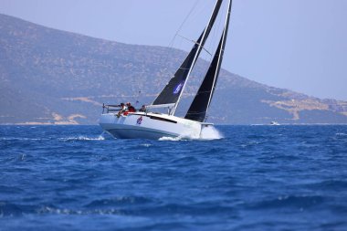 Bodrum, Hindi. 28 Nisan 2024: Yelkenliler Ege Denizi 'nin mavi sularında, ünlü tatil beldesi Bodrum' un kıyılarında rüzgarlı havada yelken açıyorlar..