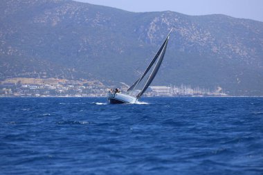 Bodrum, Hindi. 28 Nisan 2024: Yelkenliler Ege Denizi 'nin mavi sularında, ünlü tatil beldesi Bodrum' un kıyılarında rüzgarlı havada yelken açıyorlar..