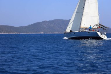 Bodrum, Hindi. 28 Nisan 2024: Yelkenliler Ege Denizi 'nin mavi sularında, ünlü tatil beldesi Bodrum' un kıyılarında rüzgarlı havada yelken açıyorlar..