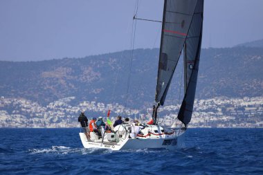 Bodrum, Hindi. 28 Nisan 2024: Yelkenliler Ege Denizi 'nin mavi sularında, ünlü tatil beldesi Bodrum' un kıyılarında rüzgarlı havada yelken açıyorlar..