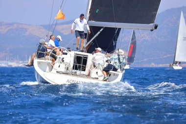 Bodrum, Hindi. 28 Nisan 2024: Yelkenliler Ege Denizi 'nin mavi sularında, ünlü tatil beldesi Bodrum' un kıyılarında rüzgarlı havada yelken açıyorlar..