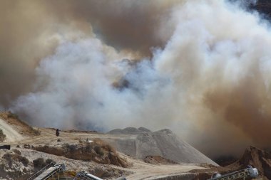 Bodrum, Hindi. 27 Temmuz 2017: Çimen tarlalarında, ormanlarda ve gökyüzüne doğru siyah beyaz dumanlar saçan kırmızı ateş alevi. Yakından büyük bir yangın var. Hava konseptinde kirlilik.