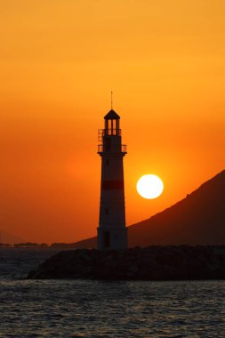 Gün ışığında deniz manzarası. Deniz feneri ve sahilde yelkenliler. Deniz kenti Turgutreis ve muhteşem güneş ışığı