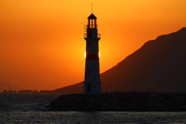Gün ışığında deniz manzarası. Deniz feneri ve sahilde yelkenliler. Deniz kenti Turgutreis ve muhteşem güneş ışığı