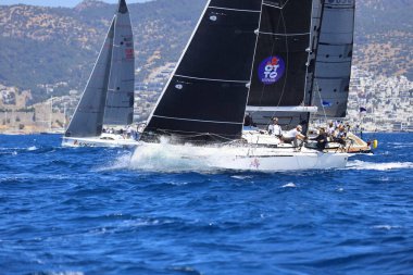 Bodrum, Hindi. 27 Nisan 2024: Ege Denizi 'nin mavi sularında, ünlü tatil beldesi Bodrum' un kıyılarında yelkenliler rüzgarlı havada yelken açıyor.