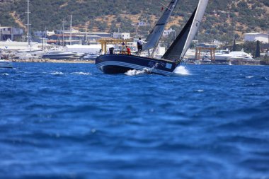 Bodrum, Hindi. 27 Nisan 2024: Ege Denizi 'nin mavi sularında, ünlü tatil beldesi Bodrum' un kıyılarında yelkenliler rüzgarlı havada yelken açıyor.