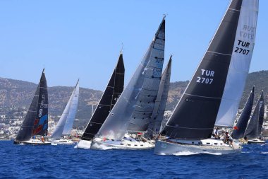 Bodrum, Hindi. 27 Nisan 2024: Ege Denizi 'nin mavi sularında, ünlü tatil beldesi Bodrum' un kıyılarında yelkenliler rüzgarlı havada yelken açıyor.