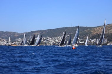 Bodrum, Hindi. 27 Nisan 2024: Ege Denizi 'nin mavi sularında, ünlü tatil beldesi Bodrum' un kıyılarında yelkenliler rüzgarlı havada yelken açıyor.