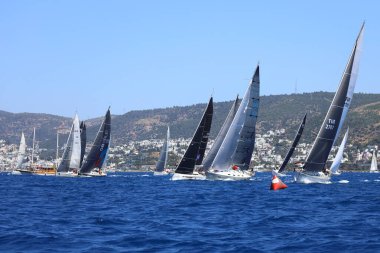 Bodrum, Hindi. 27 Nisan 2024: Ege Denizi 'nin mavi sularında, ünlü tatil beldesi Bodrum' un kıyılarında yelkenliler rüzgarlı havada yelken açıyor.