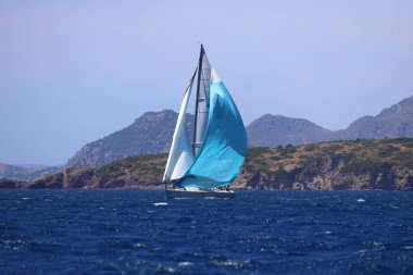 Bodrum, Hindi. 27 Nisan 2024: Ege Denizi 'nin mavi sularında, ünlü tatil beldesi Bodrum' un kıyılarında yelkenliler rüzgarlı havada yelken açıyor.
