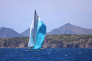 Bodrum, Hindi. 27 Nisan 2024: Ege Denizi 'nin mavi sularında, ünlü tatil beldesi Bodrum' un kıyılarında yelkenliler rüzgarlı havada yelken açıyor.