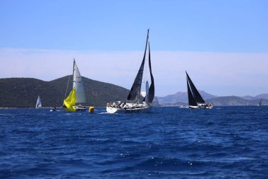 Bodrum, Hindi. 27 Nisan 2024: Ege Denizi 'nin mavi sularında, ünlü tatil beldesi Bodrum' un kıyılarında yelkenliler rüzgarlı havada yelken açıyor.