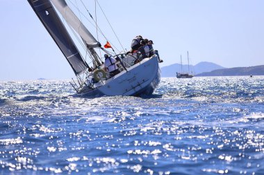 Bodrum, Hindi. 27 Nisan 2024: Ege Denizi 'nin mavi sularında, ünlü tatil beldesi Bodrum' un kıyılarında yelkenliler rüzgarlı havada yelken açıyor.
