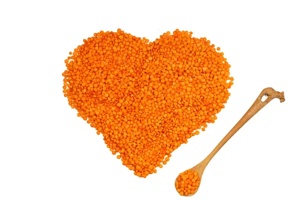 Beyaz arka planda izole edilmiş kalp şeklinde kırmızı mercimek yığını. Üst Manzara. Düz yatıyordu. Vejetaryen ve vejetaryen diyeti. Kırmızı mercimek içinde yüksek miktarda B vitamini. sağlıklı Superfood