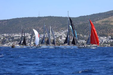 Bodrum, Hindi. 25 Mayıs 2024: Yelkenliler Ege Denizi 'nin mavi sularında, ünlü tatil beldesi Bodrum' un kıyılarında rüzgarlı havada yelken açıyor..