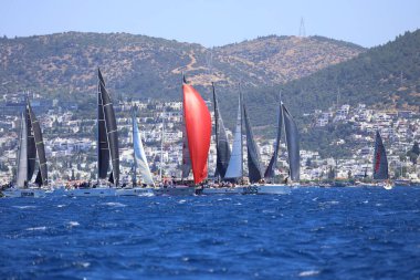 Bodrum, Hindi. 25 Mayıs 2024: Yelkenliler Ege Denizi 'nin mavi sularında, ünlü tatil beldesi Bodrum' un kıyılarında rüzgarlı havada yelken açıyor..