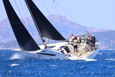 Bodrum, Hindi. 25 Mayıs 2024: Yelkenliler Ege Denizi 'nin mavi sularında, ünlü tatil beldesi Bodrum' un kıyılarında rüzgarlı havada yelken açıyor..