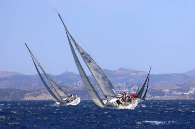 Bodrum, Hindi. 25 Mayıs 2024: Yelkenliler Ege Denizi 'nin mavi sularında, ünlü tatil beldesi Bodrum' un kıyılarında rüzgarlı havada yelken açıyor..