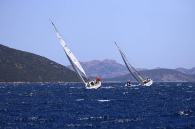 Bodrum, Hindi. 25 Mayıs 2024: Yelkenliler Ege Denizi 'nin mavi sularında, ünlü tatil beldesi Bodrum' un kıyılarında rüzgarlı havada yelken açıyor..