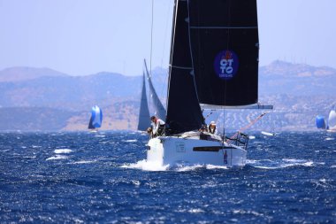 Bodrum, Hindi. 25 Mayıs 2024: Yelkenliler Ege Denizi 'nin mavi sularında, ünlü tatil beldesi Bodrum' un kıyılarında rüzgarlı havada yelken açıyor..