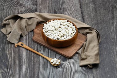 Ahşap arka planda izole edilmiş tahta kasede beyaz böbrek fasulyesi. Üst Manzara. Düz yatıyordu