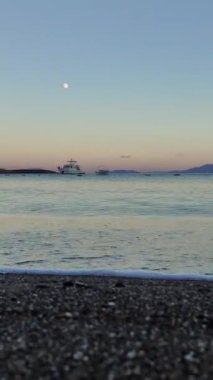 Dolunayda gün doğumunda iki teknesi olan deniz manzarası. sosyal medya için dikey video.