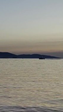 Denizde yelkenli. Denizin üzerinde deniz manzaralı altın gün doğumu. Gündoğumunda yat gezintisi. Güzel bir yelkenli ile deniz manzarası. Yelkenliyle turizm turizmi yapıyor. Dikey video.