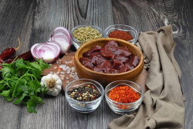 Çiğ sığır ciğerini soğan, baharat, kırmızı biber ve ahşap masada dereotla kes.