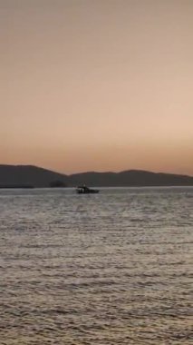 Denizde yelkenli. Denizin üzerinde deniz manzaralı altın gün doğumu. Gündoğumunda yat gezintisi. Güzel bir yelkenli ile deniz manzarası. Yelkenliyle turizm turizmi yapıyor. Dikey video.
