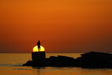 Ünlü tatil beldesi Bodrum 'da turistler gün batımında balık tutarak vakit geçirirler..