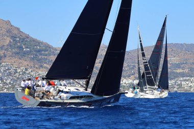 Bodrum, Hindi. 19 Ekim 2024: Yelkenliler Ege Denizi 'nin mavi sularında, ünlü tatil beldesi Bodrum' un kıyılarında rüzgarlı havada yelken açıyorlar..