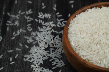 Ahşap arka planda çiğ beyaz pirinç. Ahşap tabakta uzun pişmemiş pirinç. Doğal organik gıda. Geleneksel Asya mısır gevreği kültürü.