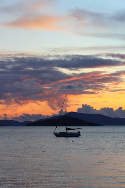 Günbatımında yalnız yelkenliler. Yansımalı atmosferik deniz manzarası