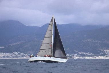 Bodrum, Hindi. 12 Ocak 2025: Yelkenliler Ege Denizi 'nin mavi sularında, ünlü tatil beldesi Bodrum' un kıyılarında rüzgarlı havada yelken açıyorlar..