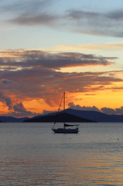 Günbatımında yalnız yelkenliler. Yansımalı atmosferik deniz manzarası