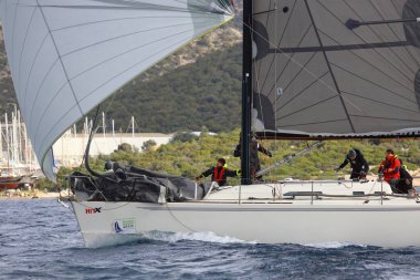 Bodrum, Hindi. 12 Ocak 2025: Yelkenliler Ege Denizi 'nin mavi sularında, ünlü tatil beldesi Bodrum' un kıyılarında rüzgarlı havada yelken açıyorlar..