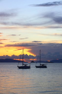 Günbatımında yalnız yelkenliler. Yansımalı atmosferik deniz manzarası