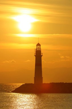 Gün ışığında deniz manzarası. Deniz feneri ve sahilde yelkenliler. Deniz kenti Turgutreis ve muhteşem güneş ışığı