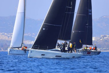 Bodrum, Hindi. 08 Mart 2025: Yelkenliler Ege Denizi 'nin mavi sularında, ünlü tatil beldesi Bodrum' un kıyılarında rüzgarlı havada yelken açıyorlar..