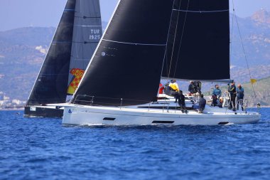 Bodrum, Hindi. 08 Mart 2025: Yelkenliler Ege Denizi 'nin mavi sularında, ünlü tatil beldesi Bodrum' un kıyılarında rüzgarlı havada yelken açıyorlar..