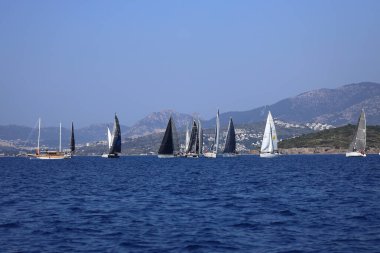 Bodrum, Hindi. 08 Mart 2025: Yelkenliler Ege Denizi 'nin mavi sularında, ünlü tatil beldesi Bodrum' un kıyılarında rüzgarlı havada yelken açıyorlar..